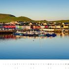 „Das alte Fischerdorf Portmagee am frühen Morgen, County Kerry.“ Bunte Häuser am Wasser, Boote und Hügel im Hintergrund.