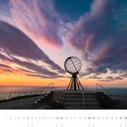 Kalendermonat November mit einem Globus auf einem Podest, dahinter ein farbenfroher Sonnenuntergang über dem Meer.