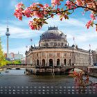 Kalenderseite mit Text "Museumsinsel 11". Historisches Gebäude an einem Fluss, blühende Zweige im Vordergrund.