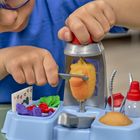 Ein Kind in blauer Kleidung benutzt ein plastisches medizinisches Spielzeug mit Formen, Pinzette und kleinen Behältern.