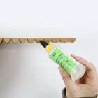 Etikettentext: "MODELLEIM, STRONG GLUE". Eine Hand trägt Kleber auf eine gezackte Kartonoberfläche auf.