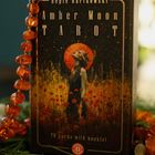 Auf der Box steht "Hepie Bartkowski Amber Moon Tarot". Eine Illustration zeigt eine Person vor einem orangefarbenen Mond.