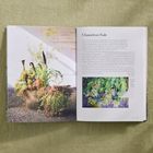 Der Text "Chameleon Fade" begleitet ein Pflanzenarrangement in einem Buch. Eine Kupfervase mit vielfältigen Pflanzenarten.