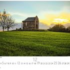 Kapelle im Sonnenuntergang. Eine kleine Kapelle steht auf einem Hügel, umgeben von grüner Wiese und einem Baum.