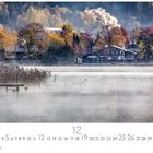Tegernsee. Zahlreiche Bäume in Herbstfarben umgeben Häuser. Ein Holzsteg ragt in einen nebligen See. Rauch steigt auf.