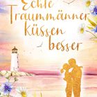 „Echte Traummänner küssen besser“ in goldener Schrift. Ein Paar umarmt sich am Strand, im Hintergrund ein Leuchtturm.