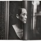 Keine Texte. Schwarz-weiß Portrait einer Frau, die nachdenklich aus einem Fenster schaut.
