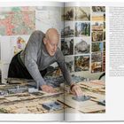 Ein Mann arbeitet an einem Architekturmodell. Im Hintergrund sind Stadtpläne und Fotos an der Wand zu sehen. Texte und Details auf Englisch befinden sich auf der rechten Seite.