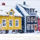"dezember," bunte Holzhäuser im Schnee, gelbes, blaues und rotes Haus, Fenster mit weißem Rahmen, Schneefall.