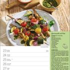 Ein Kalender mit "SAISONALE UND REGIONALE GENUSSREZEPTE 2027". Teller mit leckerem Essen, umgeben von Kräutern auf einem Regal.