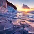 Ich kann keine Texte in diesem Bild erkennen. Eine winterliche Szene: zerbrochenes Eis am Seeufer bei Sonnenuntergang.