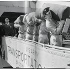 "U.S. Army Transportation, Brooklyn." Soldaten tragen Säcke, ein Offizier steht daneben. Ein Fotograf ist im Hintergrund.