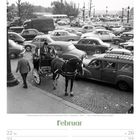 Kalender mit "Februar" unten, Woche 8 von 2027. Schwarzweiß-Szene: Viele Autos, Pferdekutsche, Menschen, Eiffelturm im Hintergrund.