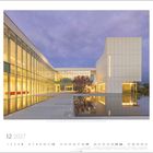 "12 2027" am oberen Rand, Kalenderunterseite. Modernes Gebäude mit Glasfassaden, Wasserreflektion und Abendbeleuchtung.