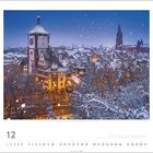 Freiburg im Breisgau, Baden-Württemberg. Winterliche Stadtansicht mit Schnee auf Dächern und einem beleuchteten Turm. Kalenderblatt.
