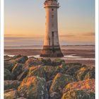 Dezember 2027 Kalender. Ein Leuchtturm steht auf felsigem Ufer im Sonnenuntergang. Wolken über sanftem Himmel.