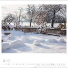 12 2027. Ein verschneiter Garten mit Bäumen und einem Holzzaun im Hintergrund. Kalenderdaten darunter.