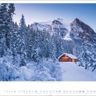 12 unten. Tief verschneite Hütte in einem dichten, schneebedeckten Wald vor hohen Bergen im Hintergrund.