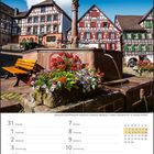 Zahlreiche Fachwerkbauten umsäumen Schiltachs Marktplatz. Brunnen mit Blumen, Bänken und Fachwerkhäuser im Hintergrund.