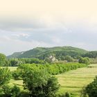 Text: "LAND UND LEUTE." Landschaft mit Wiesen, Hügeln und vielen Bäumen im Vordergrund, Fluss im Vordergrund.