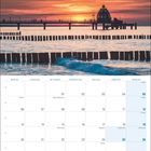 Dezember 2027 Kalender mit Feiertagen. Oben Sonnenuntergang über einem Steg am Meer, sanfte Wellen im Vordergrund.
