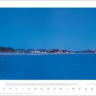 Dezember 2027, Leuchtturm zur Blauen Stunde; Küstenlandschaft, Meer mit Lichtreflexion, Häuser im Hintergrund.