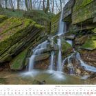 Kalenderblatt: Dezember 2027. Wasserfall Tanzlay, Eifel. Waldlandschaft mit Wasserfall über moosbedeckten Felsen.