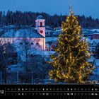 Kalendertext: „Liechtenstein 12“ und „Winter zur Weihnachtszeit in Mauren“. Ein beleuchteter Tannenbaum vor einer Kirche.
