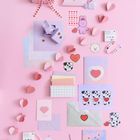 Geschenk mit Herzmotivband, Karten mit "I LOVE YOU" und "BEST FRIENDS". Rosa Hintergrund, Herz- und Tierillustrationen.