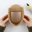 Braune Papierschale in Händen, daneben eine Flasche Klebstoff mit schwarzem Deckel und grünem Etikett.