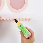 Eine Hand hält "BASTELKLEBER Fine Glue" unter pastellfarbener Papierdeko.