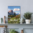 „Die Alpen 2021“ steht auf einem Kalender. Er hängt über einem Regal mit Pflanzen und Küchenutensilien.