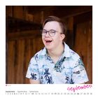 Melvin, September. Ein junger Mann mit Brille, tropischem Hemd vor Holz, lachend. Kalender unten, September fett pink.