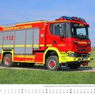 Ein rotes Löschfahrzeug der Feuerwehr Markt Schwaben auf einem Feldweg, umgeben von grünem Gras und blauem Himmel.
