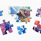 Bunte Puzzleteile zeigen Meeresszenen, Krebstiere und Pflanzen vor blauem Hintergrund. Einige Teile sind zusammengesteckt.