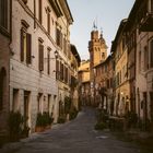 Schmale Kopfsteinpflasterstraße, gesäumt von alten Gebäuden, mit einem Kirchturm im Hintergrund.