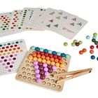 Text: "montessori". Ein Spiel mit bunten Holzkugeln, Mustervorlagen und einer Holzzange zum Platzieren der Kugeln.