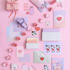 Auf rosa Hintergrund liegen Karten mit "I LOVE YOU" und "BEST FRIENDS", Geschenkboxen, Herzaufkleber und Dekoration.