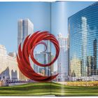 Gebäudetext: "NIVE". Rote Spiralskulptur vor moderner Skyline mit Glasfassaden und historischem Gebäude im Vordergrund.