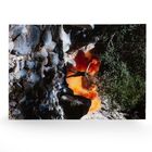 Ein Mensch breitet Arme aus, steht vor Rauchwolken in einer felsigen Landschaft.