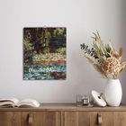 Ein Kalender mit "2027" oben und "Claude Monet" unten. Gemälde einer Brücke über einem Seerosenteich, daneben Bücher und Vase.