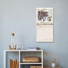 Kalenderseite Januar 2022 mit winterlicher Illustration einer Hütte im Schnee. Darunter ein Regal mit Flasche und Büchern.