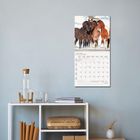 Kalenderblatt mit "Januar 2027" zeigt eine Gruppe von vier Pferden im Schnee. Darunter ein Regal mit Dekoration.