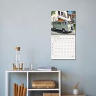 FEBRUAR 2027: Kalender mit Bild eines Oldtimer-Vans. Steht an einer weißen Wand über einem Regal mit Dekoration.