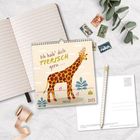 Kalender mit „Ich hab' dich tierisch gern“ und „2027“, Illustration einer Giraffe. Daneben ein Notizbuch, Postkarten, Stift, Pflanzen.