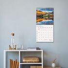 Kalenderblatt für November 2023. Foto einer Landschaft mit Bergen und einem See. Auf einem Tisch stehen Bücher und eine Karaffe.