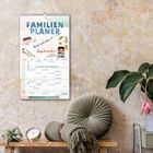 „Familienplaner“, „Macht euch schön“, „September“. Rustikale Wand mit Pflanze, Kissen und Uhr auf einem Tisch.