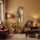 "AFRIKA 2027". Ein Poster mit Löwe und Jungem, in einem gemütlichen Raum mit Pflanzen, Körben und Holzdekorationen.