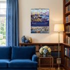 "KunstGeschichten 2027" Kalender an einer Wohnzimmerwand, blaue Couch, Bücherregal, Blumen und Stehlampe daneben.