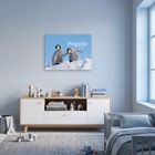 Aufhellendes Kinderzimmer. An der Wand hängt ein Kalender mit Pinguinen. Schlichter Holzschrank mit Spielzeug und Bücher.